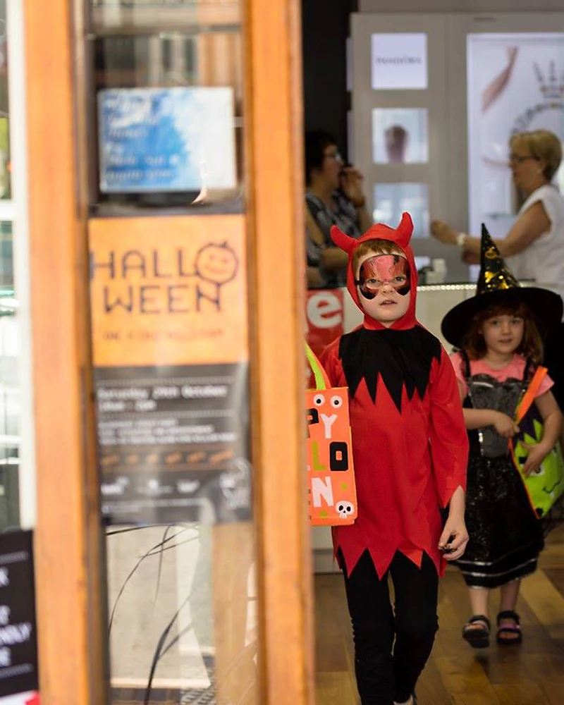 Halloween on King William poster in shopfront, with children dressed up in costumes.